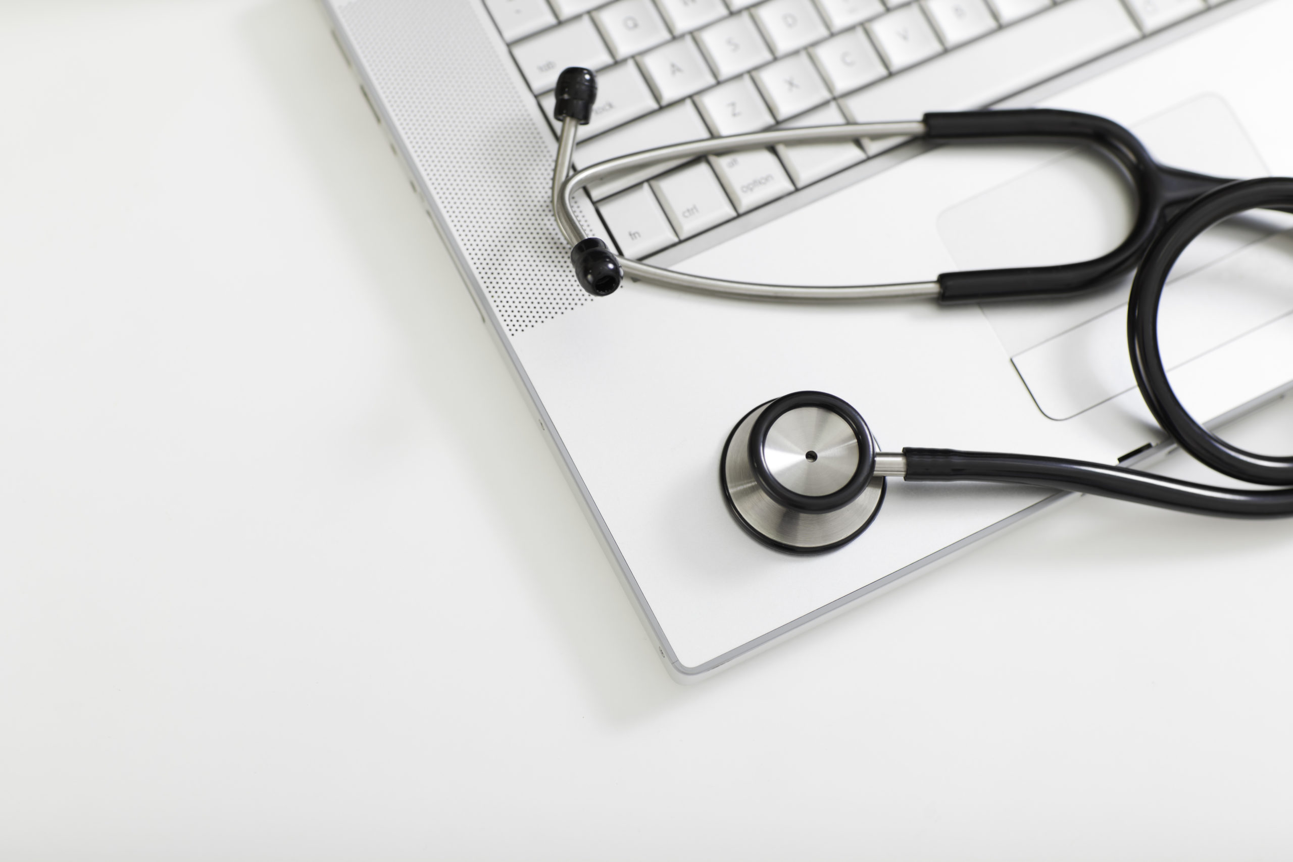 Medical stethoscope with laptop on white background